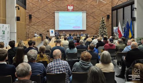 Grupa osób siedzi na sali posiedzeń.