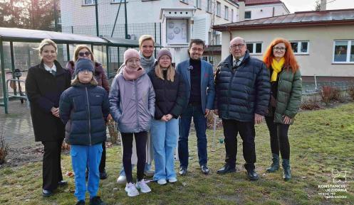 Grupa osób stoi przed stacją meterologiczną.