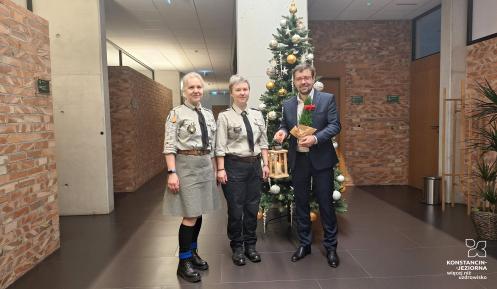 harcerki oraz burmistrz stoją w korytarzu ratusza trzymając zapalony drewniany lampion