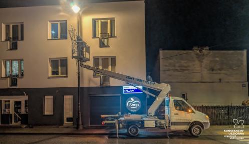 Samochód z podnośnikiem montuje dekoracje świąteczne na latarniach