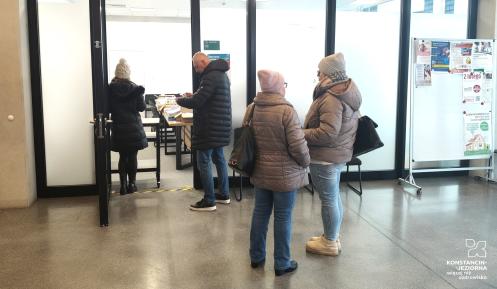 Grupa osób stoi przed wejściem do sali