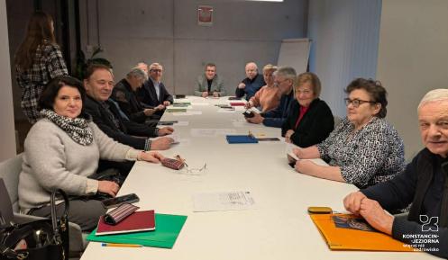 Zdjęcie grupy ludzi siedzącej przy stole w sali konferencyjnej.