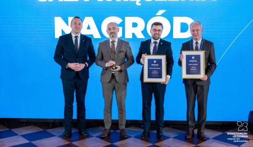 Na scenie gali wręczenia nagród przedstawiciele samorządów pozują z dyplomami i statuetką przy tle z napisem „Gala wręczenia nagród”.