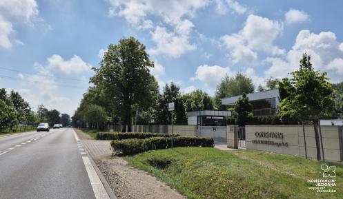 Droga wojewódzka przebiegająca przez zalesiony teren z poboczem, przy którym planowana jest budowa infrastruktury rowerowo-pieszej.