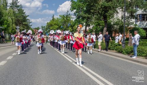 Parada z udziałem orkiestry i mażoretek przemierza ulicę podczas miejskiego święta w Konstancinie-Jeziornie.