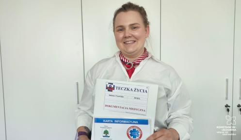 Kobieta trzyma w rękach teczkę życia, kopertę życia i kartę ICE