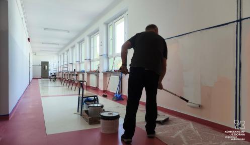 Mężczyzna maluje szkolny korytarz