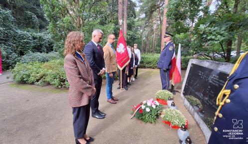 Władze gminy składają kwiaty przed pomnikiem katyńskim.
