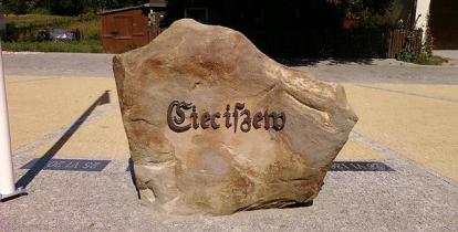 Duży brązowy kamień, na którym umieszczony jest napis – Cieciszew. Kamień stoi na placu z kostki