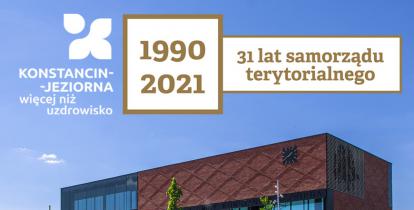 Z lewej strony znak promocyjny Konstancin-Jeziorna więcej niż uzdrowisko, pośrodku na kwadratowym polu daty 1990 2021, obok napis 31 lat samorządu terytorialnego, pod nimi nowoczesny obiekt z czerwonej cegły z licznymi oszkleniami