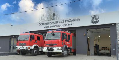 Dwa wozy strażackie, stojące przed dużym odnowionym budynkiem Ochotniczej Straży Pożarnej w Konstancinie-Jeziornie. 