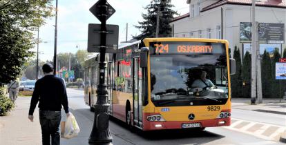 Ulica, po której jedzie czerwono-pomarańczowy autobus komunikacji miejskiej. Nad jego przednią szybą wyświetla się napis: 724 Metro Kabaty.