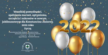 Grafika wektorowa. Na błękitnym tle białe i złote balony oraz gwiazdki. Z lewej strony życzenia od władz gminy, ich treść podana jest w artykule. Poniżej życzeń herb gminy, wokół którego umieszczono tekst: 125 lat Konstancina i 105 lat uzdrowiska Konstancin.