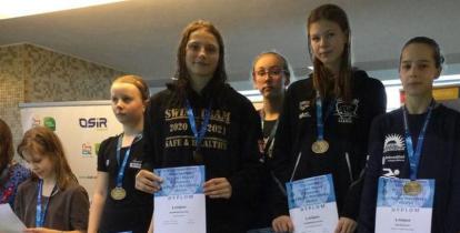 W rzędzie obok siebie stoi sześć dziewczyn. Każda na szyi ma zawieszony medal, a w rękach trzyma dyplom. 