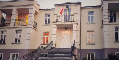 Budynek, na pierwszym planie schody, na którym są wywieszone flagi Polski i Ukrainy.