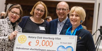 Trzy kobiety i jeden mężczyzna trzymają razem duży czek, na którym jest napisana kwota 9 tys. Euro. 