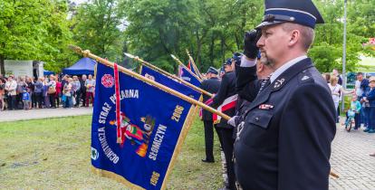 Strażacy trzymający sztandar z napisem Ochotnicza Straż Pożarna Słomczyn. 