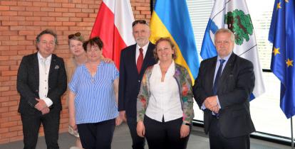 Sześć osób stojących na tle flag polskiej, ukraińskiej, unijnej oraz Konstancina-Jeziorny.