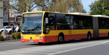 Ulica, po której jedzie czerwono-pomarańczowy autobus komunikacji miejskiej. Nad jego przednią szybą wyświetla się napis: 710 Konstancin-Jeziorna.
