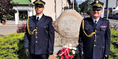 Dwóch strażników miejskich stoi przed Pomnikiem Obrońców Ojczyzny w Jeziornie.