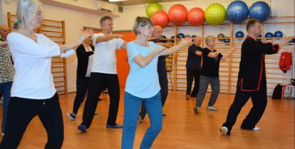 Grupa osób (seniorów) ćwiczy na sali fitness.