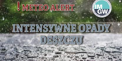 Na górze czerwony napis meteo alert poprzedzony wykrzyknikiem. Obok niego logo Instytutu Meteorologii i Gospodarki Wodnej – niebieski okrąg z białymi literami IMGW, poniżej niebieski napis intensywne opady deszczu. W tle kałuża i spadające krople deszczu.