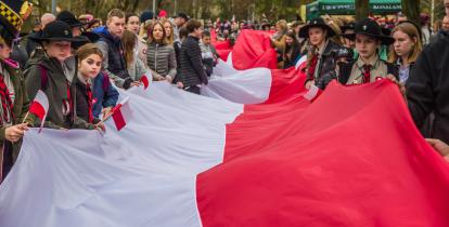 Grupa osób trzyma długą biało-czerwoną flagę.