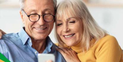 Para seniorów: kobieta i mężczyzna patrzą razem na ekran telefonu