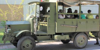 Stary wojskowy zabytkowy samochód, na którego pace siedzą uczniowie