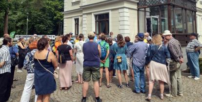 Grupa osób stoi przed budynkiem willi Kamilin