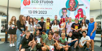 Grupa młodych ludzi pozuje do zdjęcia. Za nimi baner z napisem Eco Studio.