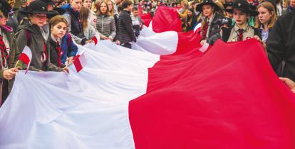 Grupa osób niesie gigantyczną biało-czerwoną flagę.