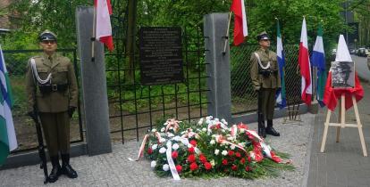 Ogrodzenie, na którym wisi tablica pamiątkowa.