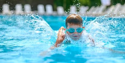 Chłopiec w goglach płycie w basenie.