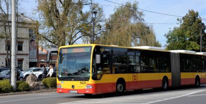 Ulica, po której jedzie czerwono-pomarańczowy autobus komunikacji miejskiej