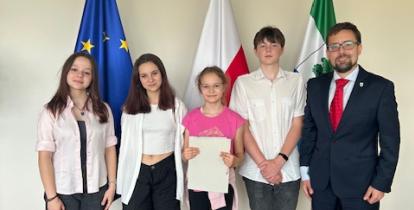 Czterech uczniów i mężczyzna w garniturze stoją obok siebie. 
