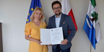 kobieta z mężczyzną trzymają otworzony dokument w tle flagi