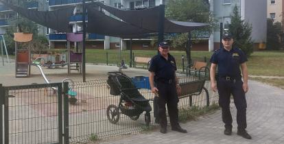 Dwóch mężczyzn w mundurach w tle plac zabaw i bawiące się dzieci.
