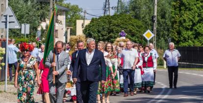 Grupa osób maszerująca środkiem drogi.