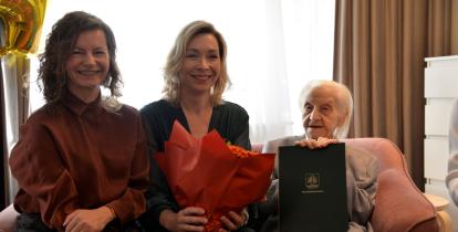 Trzy kobiety siedzą obok siebie, od lewej starsza sędziwa pani