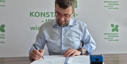 Uśmiechnięty mężczyzna podpisuje dokumenty.