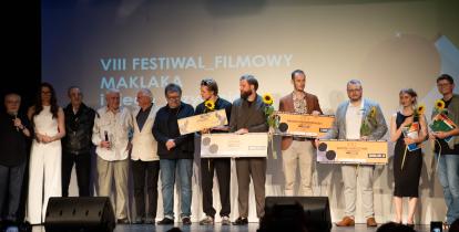Zdjęcie zbiorowe nagrodzonych osób na festiwalu - stoją na scenie w Hugonówce.