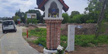 Przydrożna kapliczka przy chodniku.