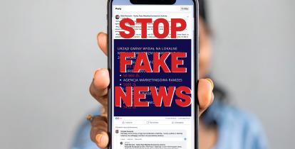 Osoba trzymająca telefon z napisem Stop Fake News