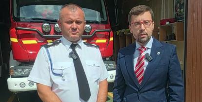 Dwóch mężczyzn na tle wozu strażackiego 