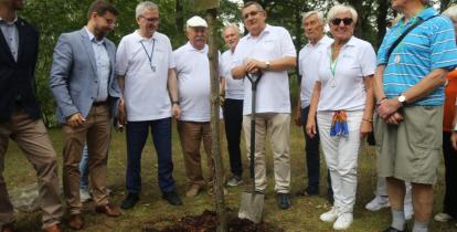 Grupa osób stoi przy drzewie.