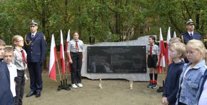 Grupa dzieci przez pomnikiem katyńskim.