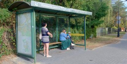 Osoby czekające na przystanku autobusowym.