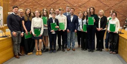 Grupa osób pozuje do zdjęcia na tle ściany z czerwonej cegły