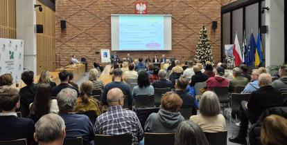 Grupa osób siedzi na sali posiedzeń.